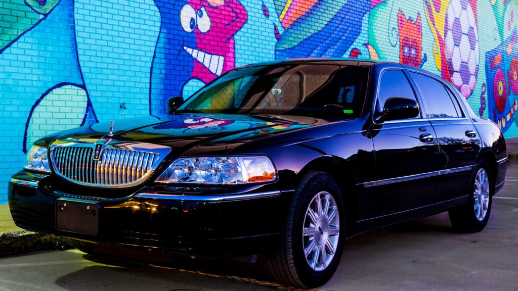 Lincoln sedan parked in front of wall with urban painting